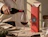 A person pouring red wine into a glass next to a tall coral-pink wine box branded 'OUR DAILY BOTTLE'