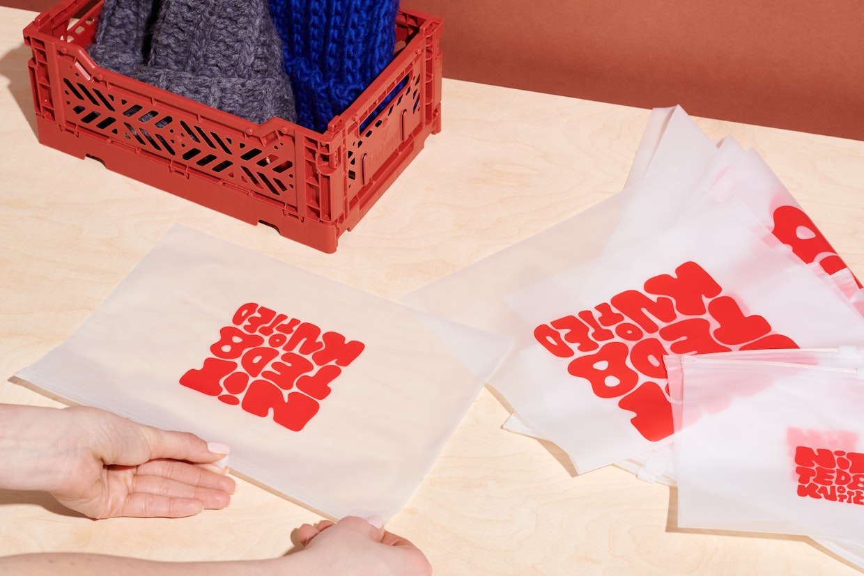 Quelques sacs Ziploc givrés avec un logo rouge et une boîte rouge contenant un chapeau bleu et un chapeau gris.