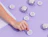 Hand placing round white custom labels on silver tins on a lilac surface