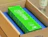 A bright green Quinta product box with floral graphics resting inside a shipping package