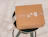 A closed cardboard box sealed with transparent tape printed with white graphics, sitting on a dark stool