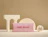 A pink pillow box branded 'sage moon JEWELRY' displayed on a beige background with geometric arch props and a pair of gold hoop earrings