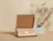 An open cardboard box containing items wrapped in brown tissue paper sealed with a 'Thank you' sticker