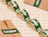 Rectangular green custom labels with white lettering on a roll, beside kraft packaging