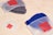 Trois sachets Ziploc givrés avec un logo rouge ; dans deux d’entre eux, il y a des bonnets, l’un bleu, l’autre gris.