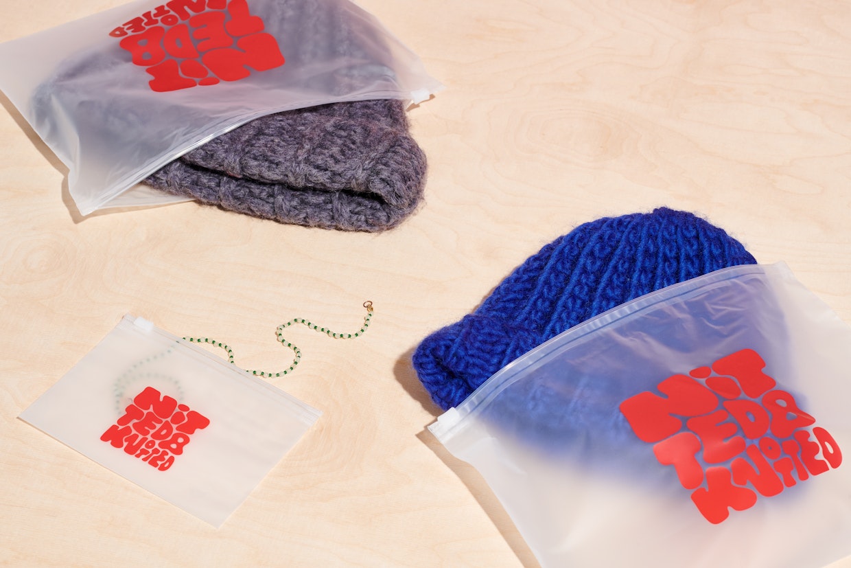Trois sachets Ziploc givrés avec un logo rouge ; dans deux d’entre eux, il y a des bonnets, l’un bleu, l’autre gris.