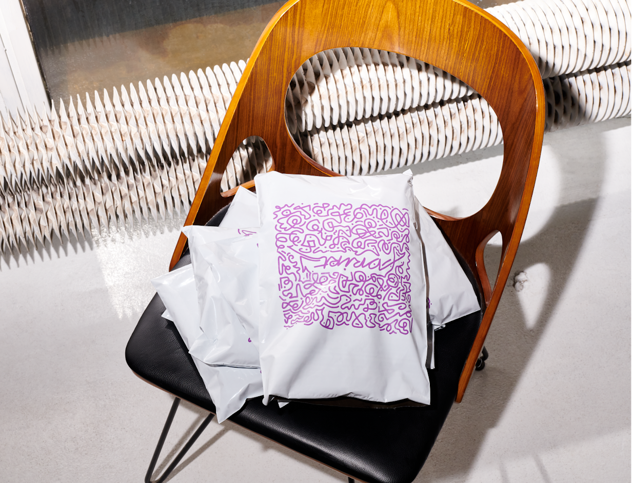 Poly mailers with a purple graphic pattern lying on a chair