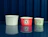Three ice cream paper cups in different sizes and designs lined up on a reflective blue table