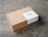 Kraft mailer box with a rectangular white custom label on the lid, on a concrete floor