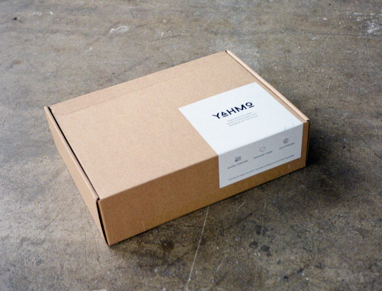Kraft mailer box with a rectangular white custom label on the lid, on a concrete floor