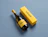 A bottle of white wine with a yellow label lying beside a yellow wine box printed with 'axtan' on a blue background
