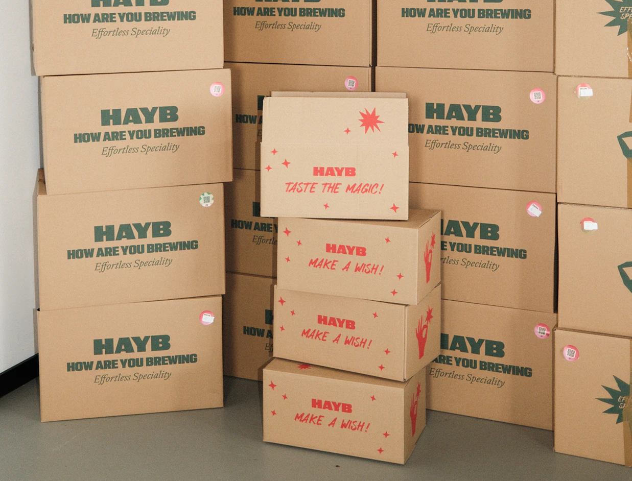 Stacked kraft shipping boxes with green and red prints in a warehouse