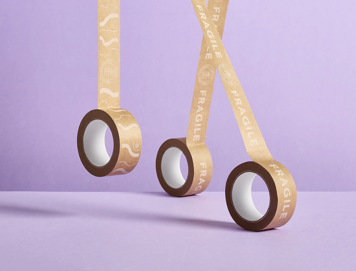 Three rolls of brown kraft paper tape printed with 'FRAGILE' text hanging in the air against a light purple background