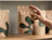 A hand reaching for a kraft paper stand-up pouch labeled 'yokō MATCHA GREEN TEA POWDER' with dark green abstract shapes, sitting on a wooden shelf
