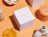 Top-down view of a white Lowrí 'AMBAR' candle box surrounded by stackable candles, an incense holder, and decorative ceramics