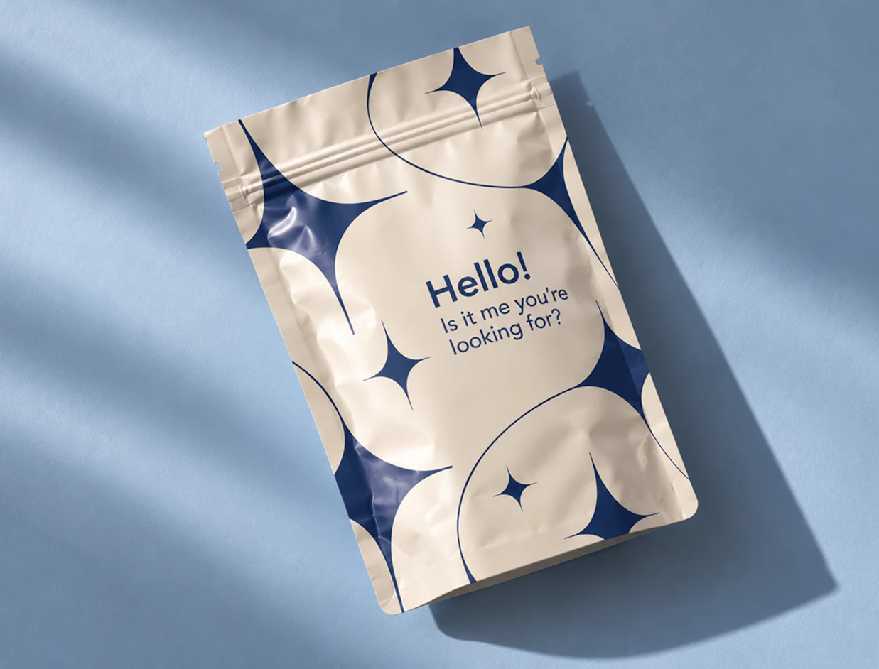 A cream stand-up pouch printed with dark blue star patterns and the text 'Hello! Is it me you're looking for?' on a blue background