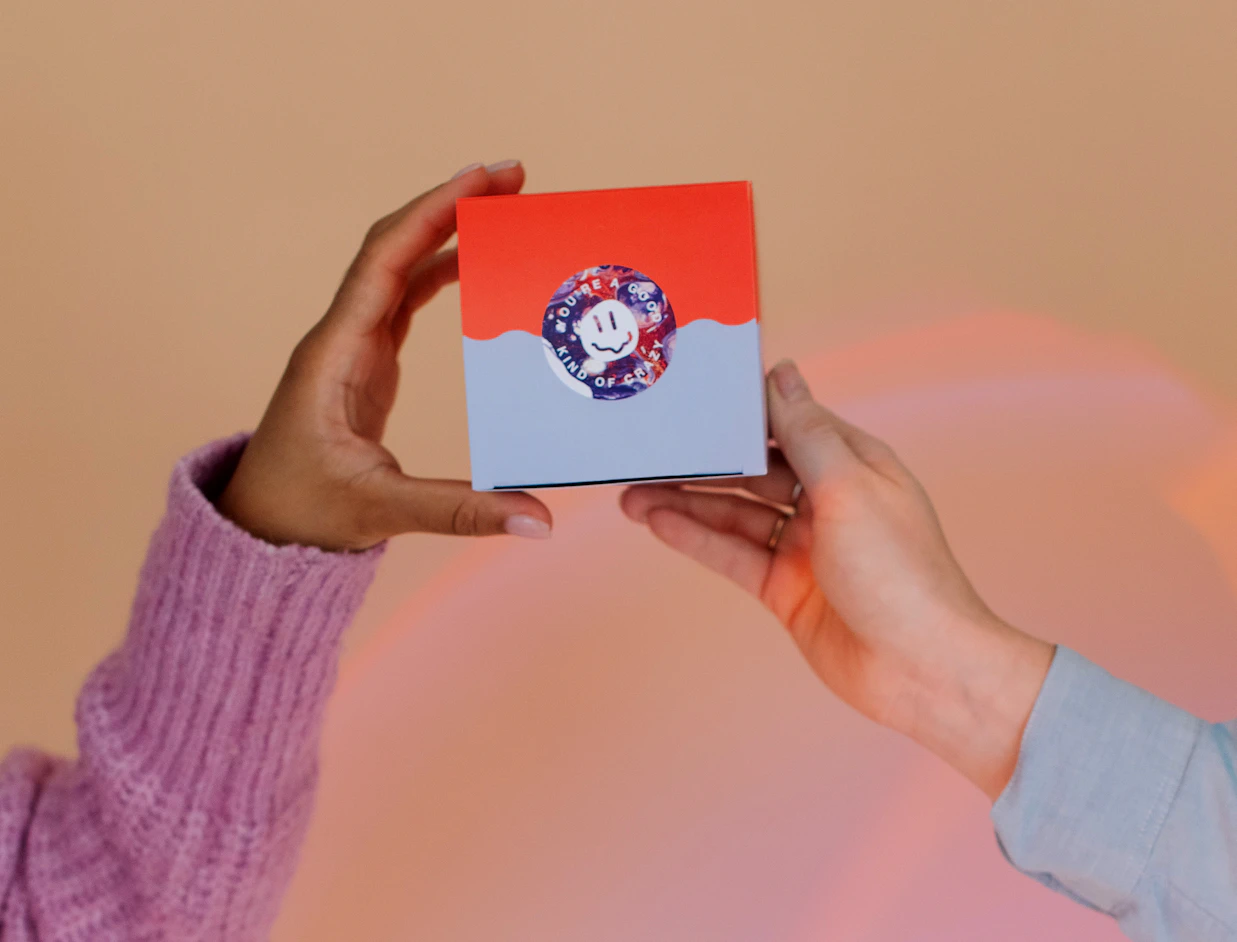 Hands holding a small box sealed with a round custom label