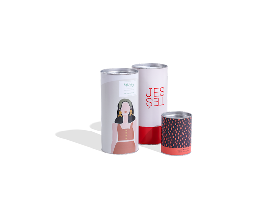  Drei bunte Tubenverpackungen mit Aufdrucken – eine mit einer Frauenillustration, eine mit Text, eine mit rosa Punkten.