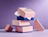 A stack of pink and blue dotted gift boxes branded 'FACETORY' surrounded by geometric foam shapes on a purple background