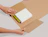 Hands wrapping books into an adjustable kraft cardboard book mailer packaging on a light background