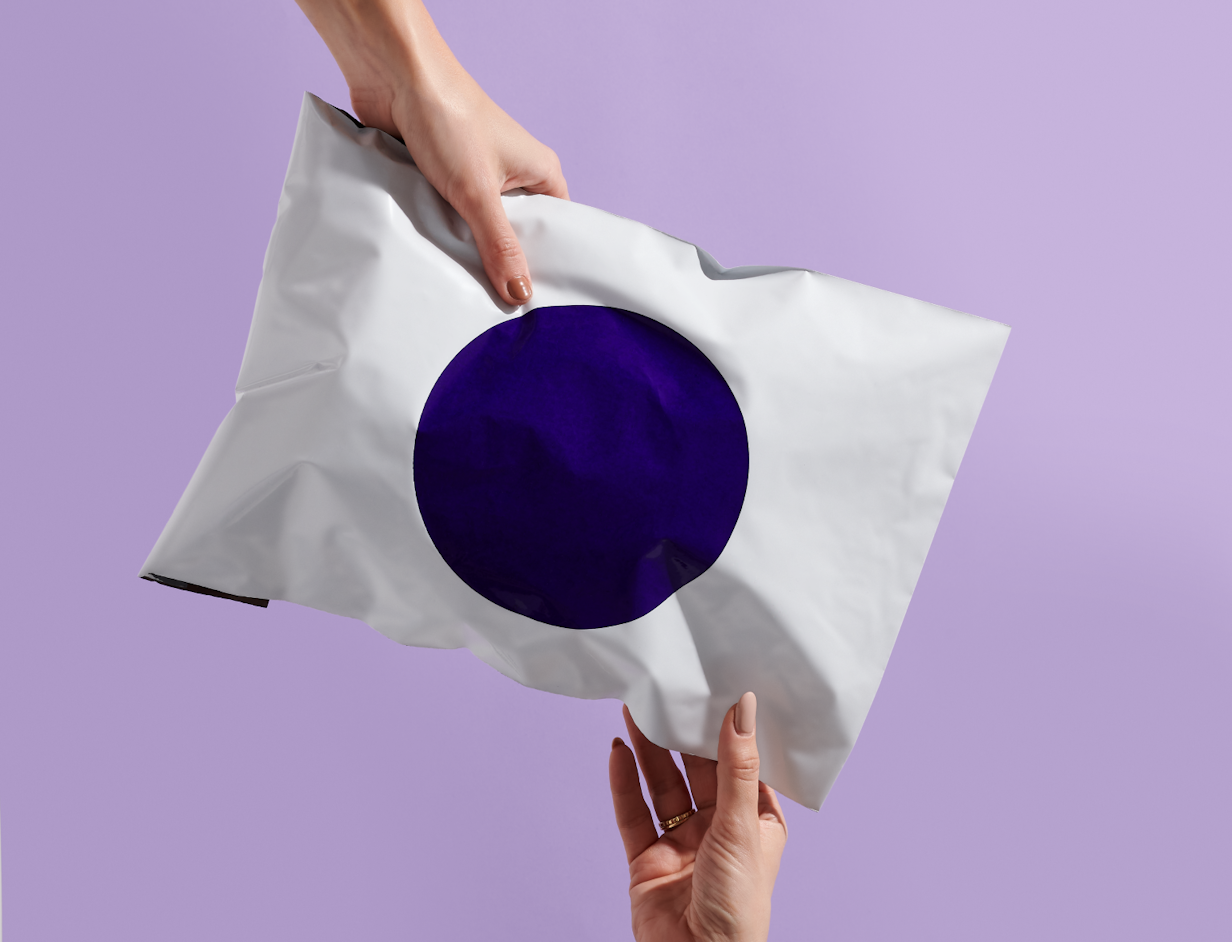 A white poly mailer with a purple circle graphic, held in both hands