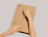 Hands opening a sealed kraft cardboard book mailer using the integrated tear strip