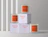 Three glass candles with orange labels and white packaging boxes printed with 'Morning Vibes', arranged in a stack against a grey wall