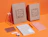 A collection of stationery items including notebooks, pens, and cardboard shipping boxes with 'NOTABLE-NOTEBOOKS.COM' branding on an orange background