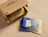 A blue coffee bag labeled 'HAYB BLUE ESPRESSO BLEND' lying next to an open cardboard shipping box containing a yellow coffee pouch