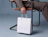 A person in a suit seated on a chair holding a blank white paper shopping bag with rope handles
