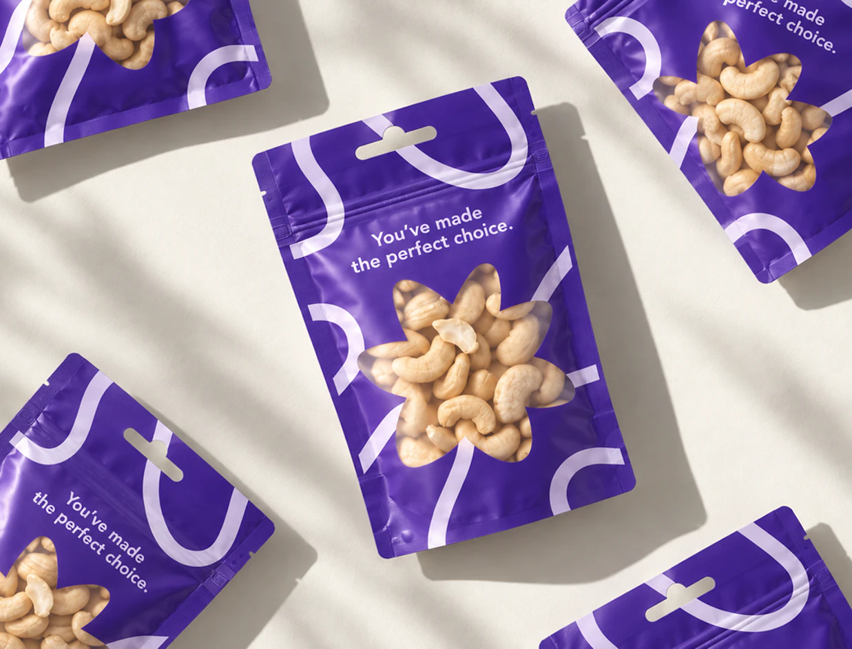 Multiple purple stand-up pouches with euro-hang tabs and flower-shaped clear windows displaying cashew nuts