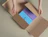 Top-down view of hands packing blue and purple books into a cardboard book wrap box with adjustable side flaps