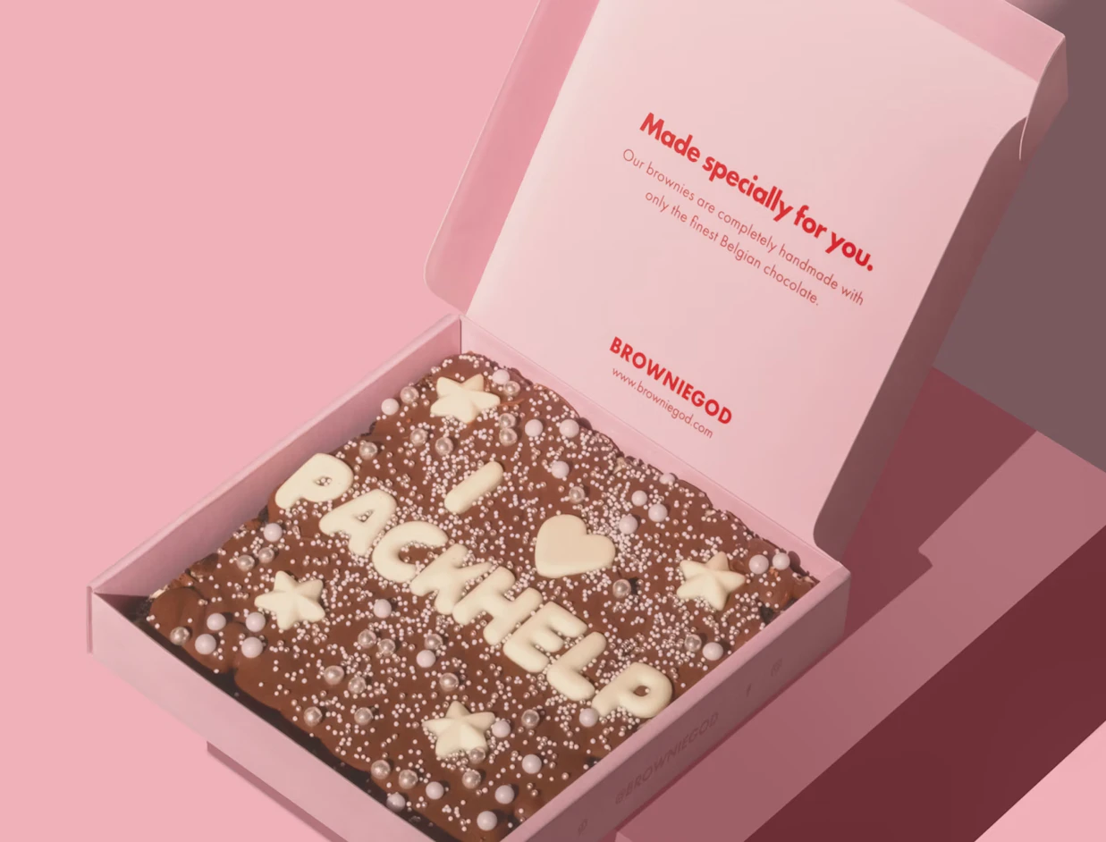 Open pink full colour mailer box with a printed message inside the lid, holding a chocolate bar