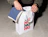 A person placing a blue waffle towel into a white gift bag printed with festive 'HO HO HO' typography