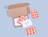 An open cardboard shipping box with patterned orange insert cards and a white 'thank you!' note