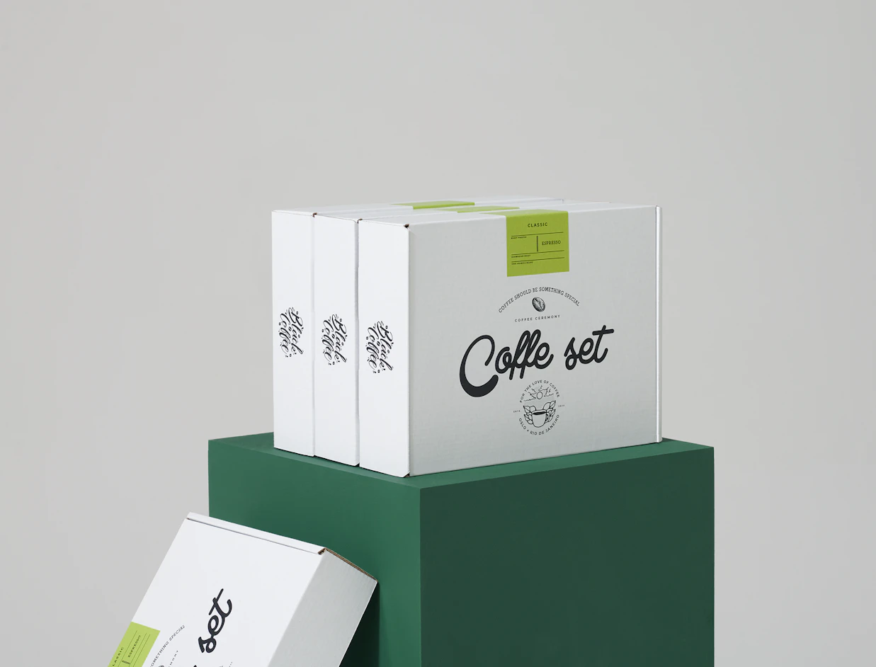 Stack of white eco mailer boxes with a one-colour black logo print, displayed on a green stand