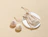 A beige drawstring cotton pouch labeled 'Bubbly' on a white circular display stand next to two round bath bombs