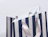Close-up of a blue and white striped paper gift bag with grey satin ribbon handles