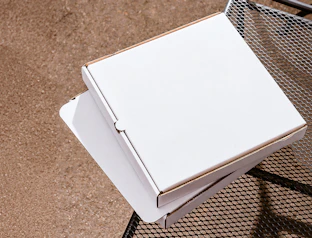 Top-down view of two plain white cardboard pizza boxes stacked on a outdoor metal mesh table