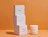Three stacked white Lowrí candle boxes next to an unlit white candle and a match stick on an orange background