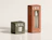 Two 'om.' skincare boxes with cutout windows revealing a cream jar in a green box and a spray mist bottle in a terracotta box