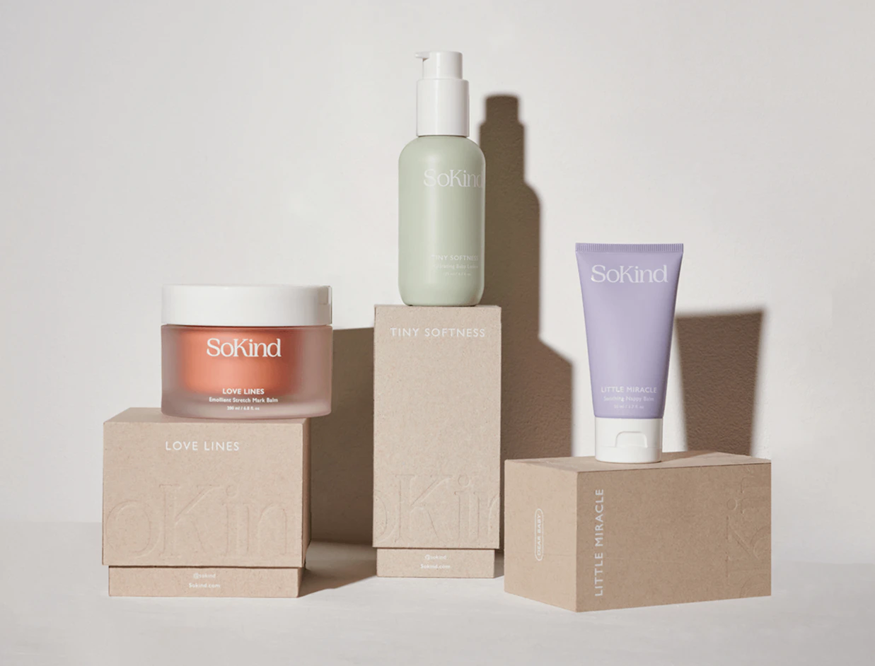 SoKind skincare products arranged on top of neutral cardboard boxes against a white wall