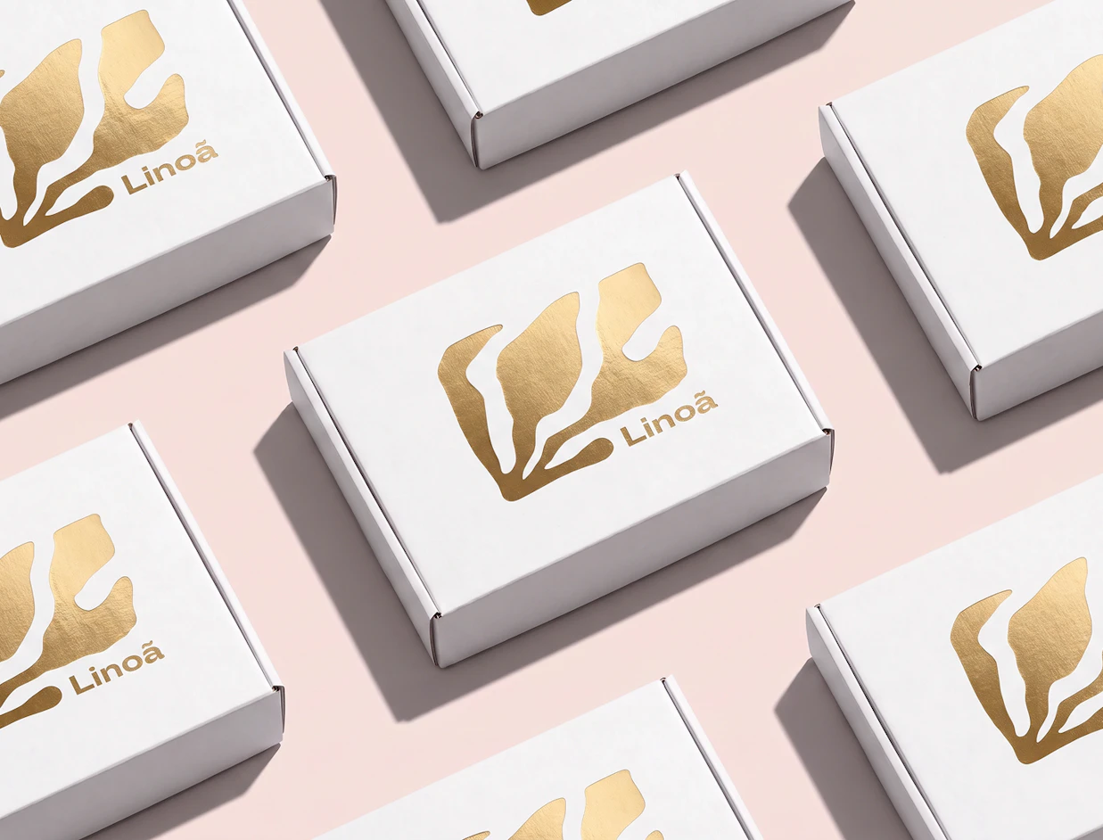 Seamless pattern layout of white cardboard boxes featuring a gold foil 'Linoã' logo on a light pink background
