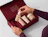 Hands opening a deep red rigid box with custom molded inlay holding TETE skincare bottles and jars, with 'YOUR NEW FAVOURITE SKIN CARE' printed inside the lid