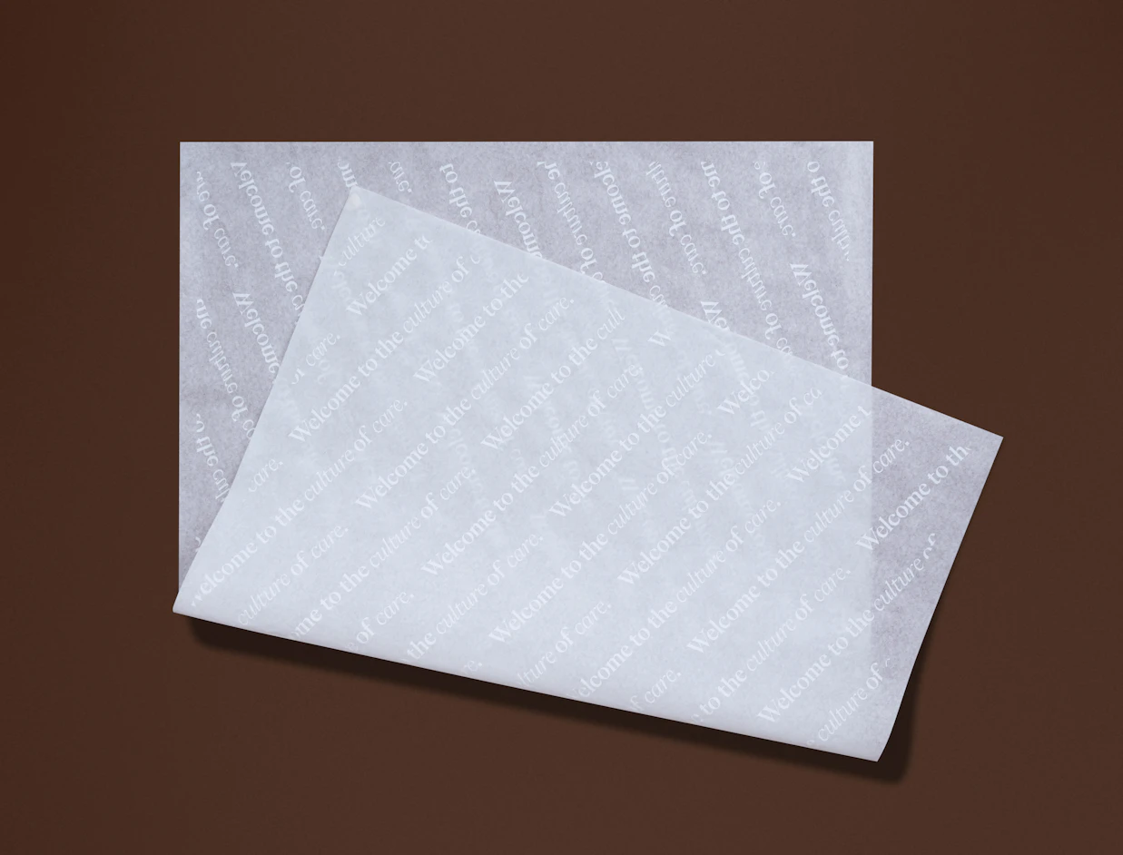 Two sheets of white tissue paper with a diagonal white text print on a brown background