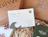 A white thank you card with a wave design placed inside a box filled with wood wool, branded with 'alma IRELAND'