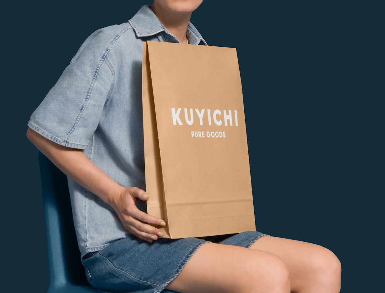 Person seated holding an expandable kraft mailer with a white logo print