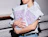 A person holding a large stack of white shipping bags covered in purple doodle art patterns