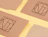 Flat lay of brown craft paper mailers printed with geometric 'NT' logos on a light yellow background