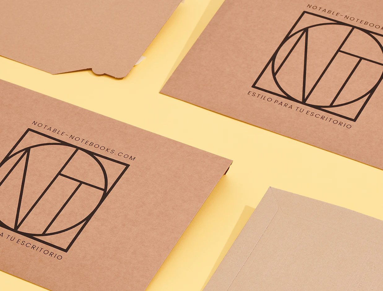 Flat lay of brown craft paper mailers printed with geometric 'NT' logos on a light yellow background
